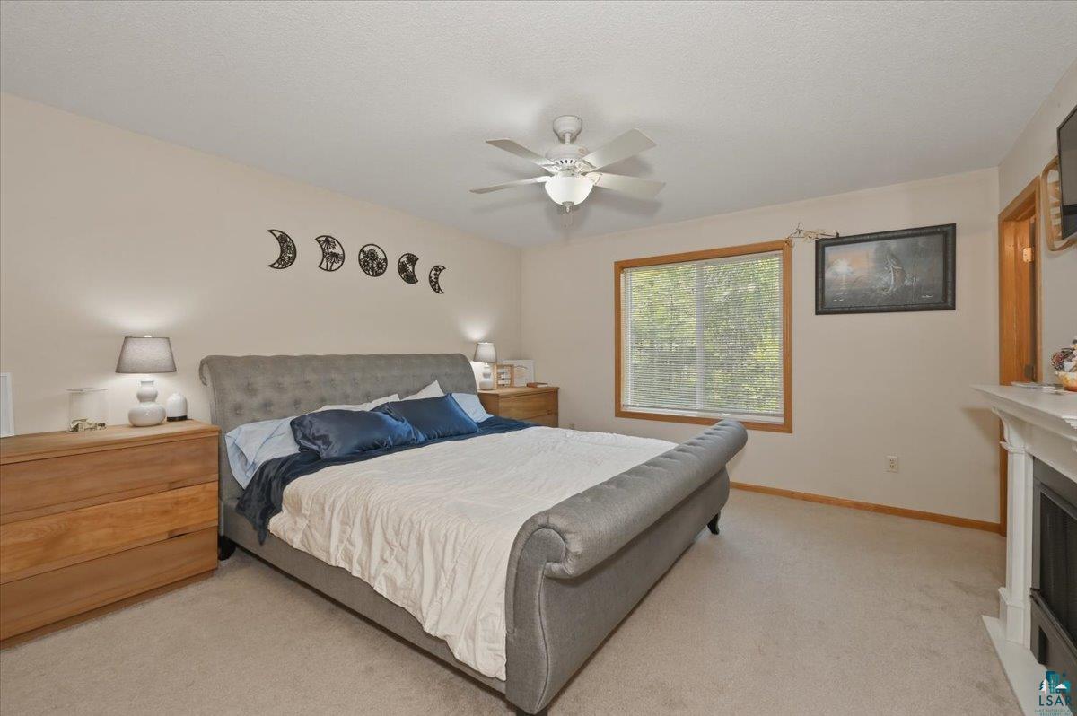 47 Amy Lane Esko, MN 55733 - Photo 18 of 33 Carpeted room featuring a ceiling fan, a window with wood trim, and a built-in fireplace with a white mantel