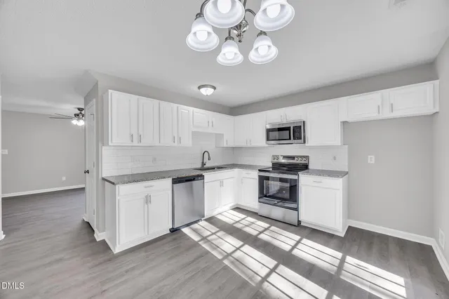 a kitchen with stainless steel appliances granite countertop a stove top oven a sink dishwasher and a refrigerator with wooden floor