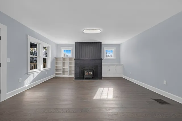 a view of empty room with wooden floor and fireplace