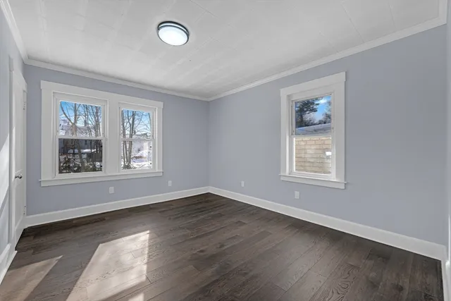 a view of an empty room with wooden floor and window