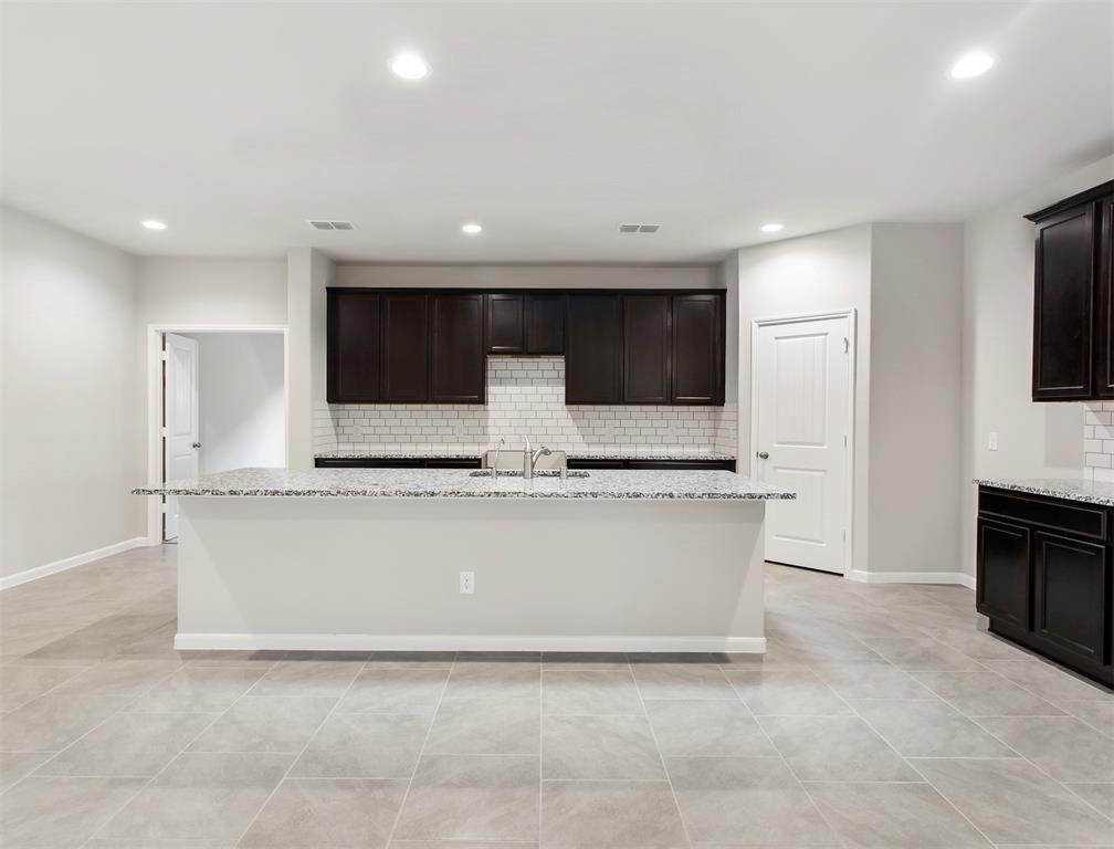 a large kitchen with kitchen island granite countertop a sink and a stove top oven