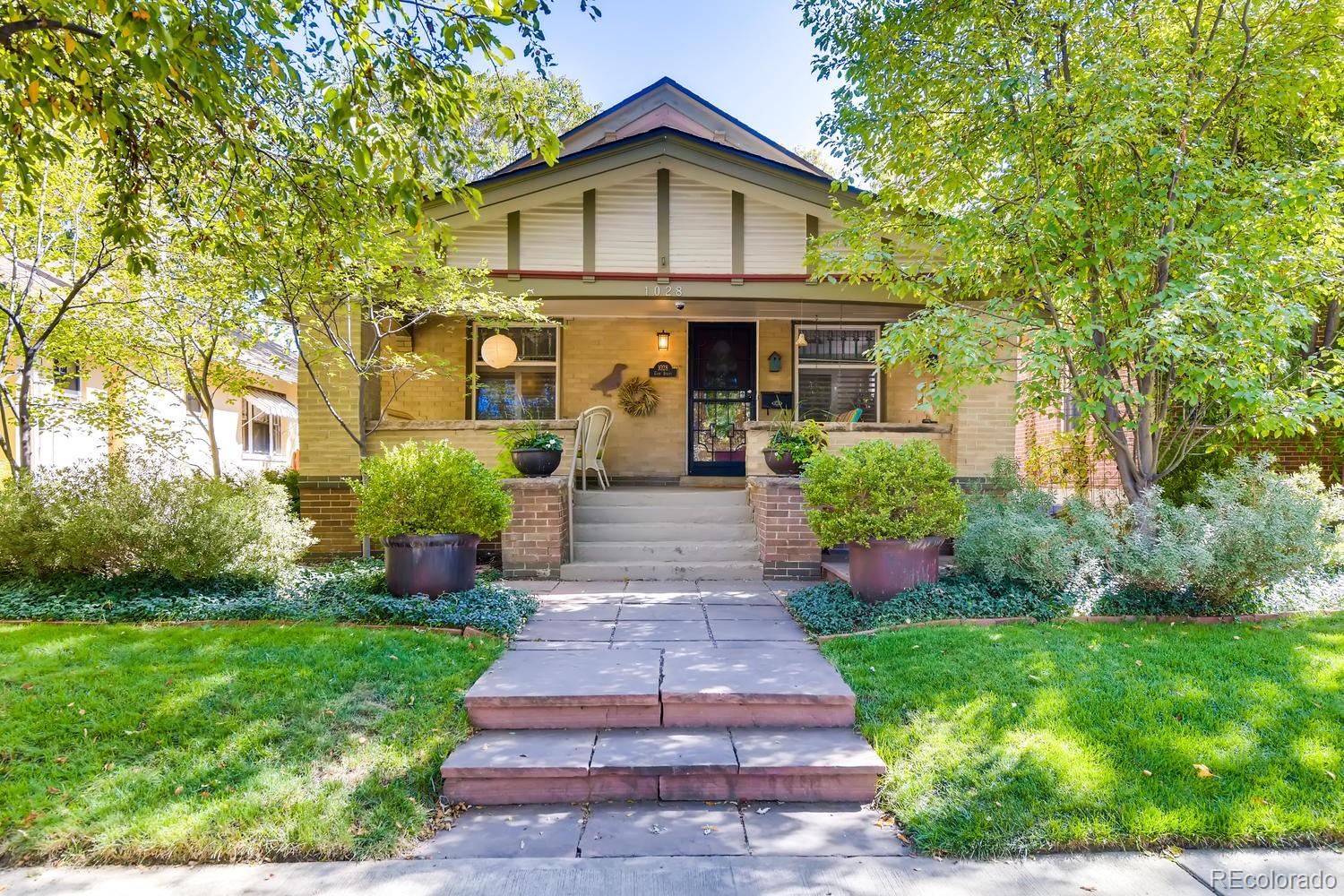 a front view of a house with a yard and potted plants
