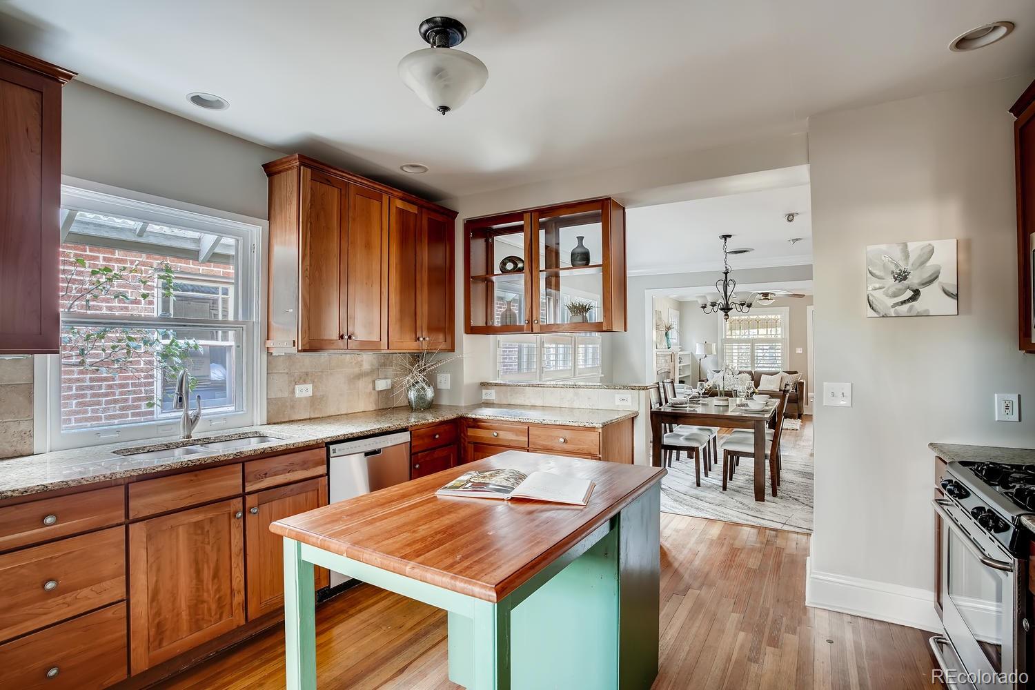 1028 Cook Street Denver, CO 80206 - Photo 13 of 40 a kitchen with stainless steel appliances granite countertop sink stove and wooden cabinets