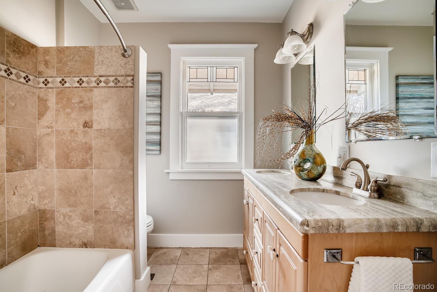 1028 Cook Street Denver, CO 80206 - Photo 24 of 40 a bathroom with a granite countertop sink a mirror and shower