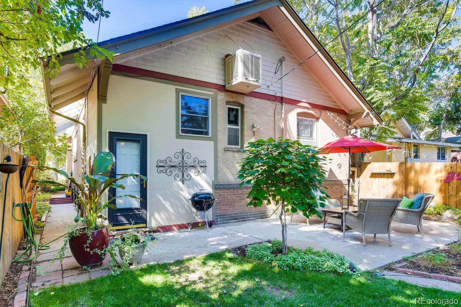 1028 Cook Street Denver, CO 80206 - Photo 33 of 40 a backyard of a house with table and chairs potted plants and large tree