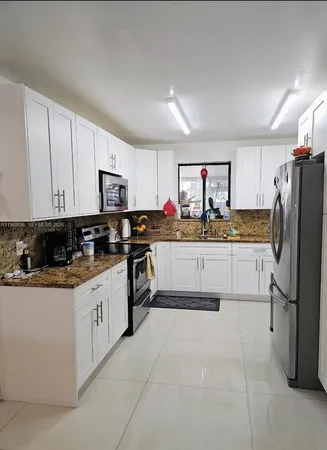a kitchen with stainless steel appliances granite countertop a refrigerator sink and white cabinets