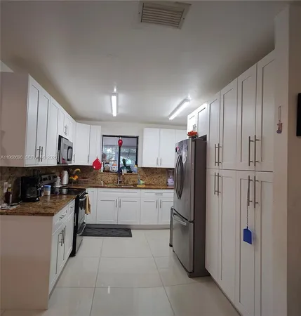 a kitchen with stainless steel appliances granite countertop a refrigerator and a stove top oven