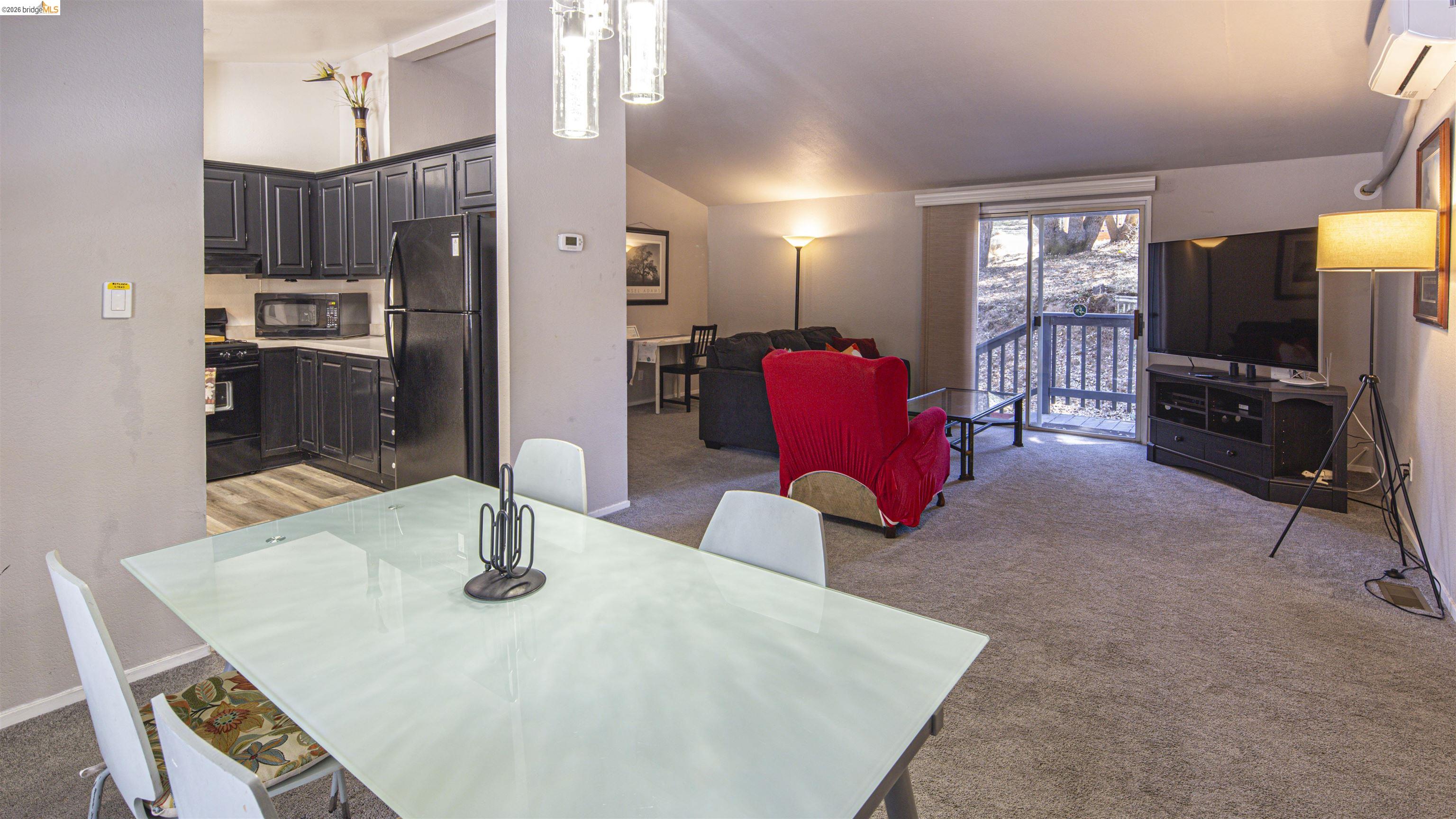 19327 Ferretti Road Groveland, CA 95321 - Photo 18 of 44 Dining area with a frosted glass-top table, overhead pendant lighting, and an adjoining kitchen featuring black cabinetry and appliances