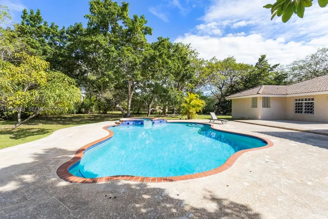 a view of house with swimming pool and yard