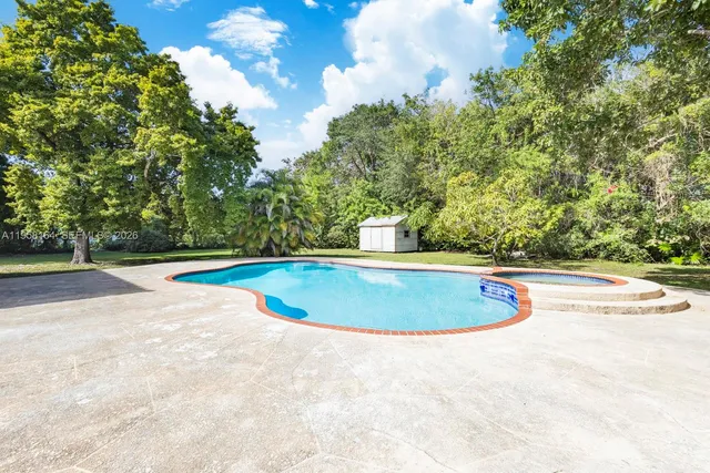 a view of house with swimming pool and yard