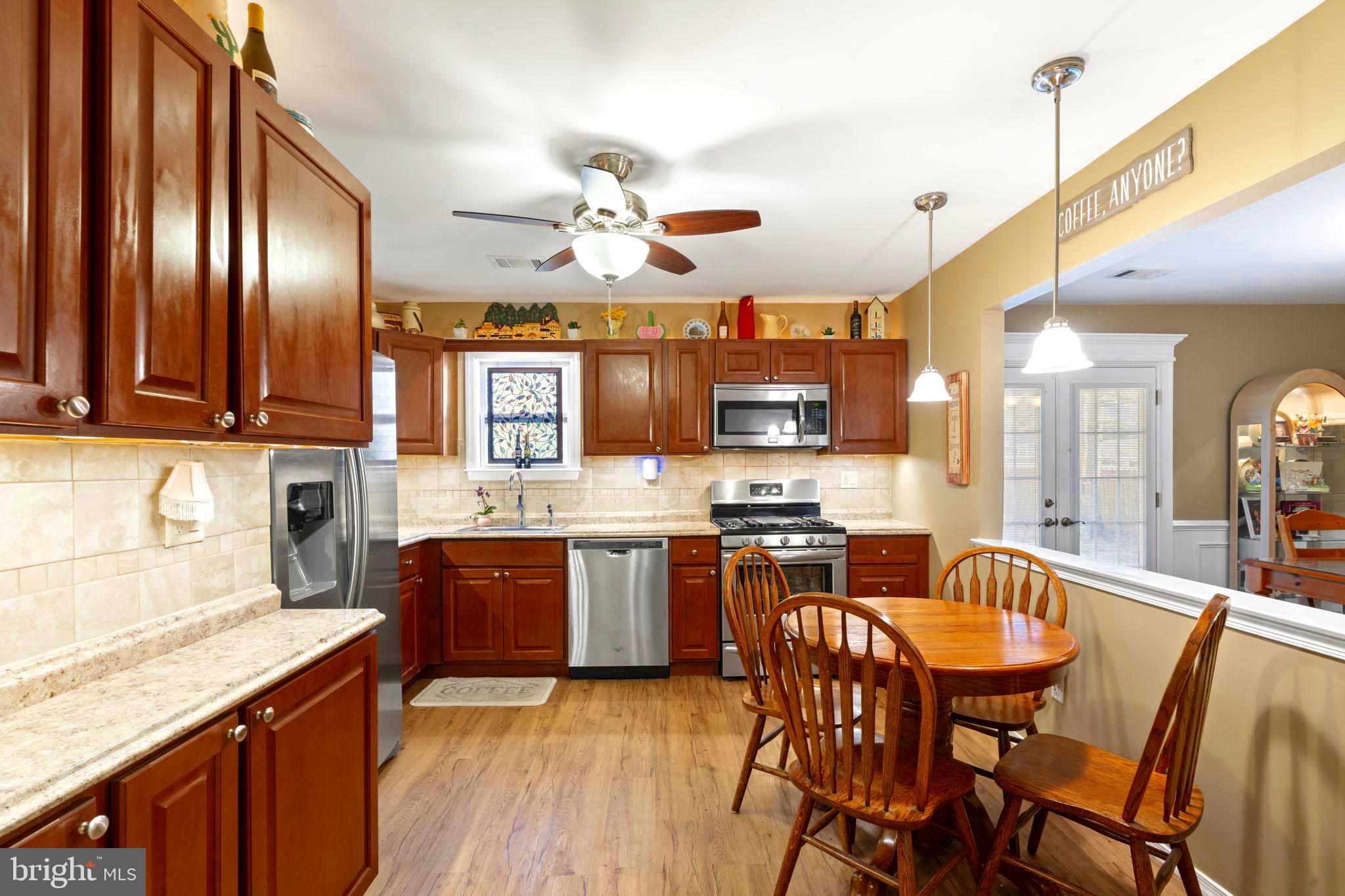 78 Lupus Lane Sewell, NJ 08080 - Photo 9 of 45 a kitchen with stainless steel appliances granite countertop a stove top oven a sink dishwasher a dining table and chairs with wooden floor