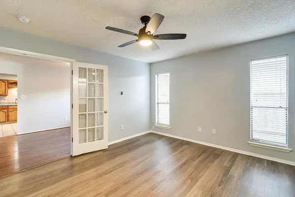 a view of an empty room with wooden floor and a window