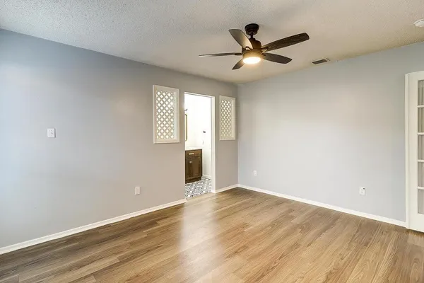 an empty room with wooden floor and windows