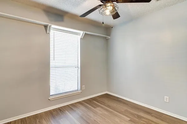 an empty room with a window and wooden floor