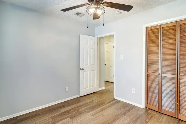 an empty room with wooden floor chandelier and windows
