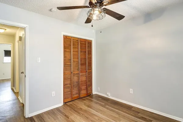 an empty room with wooden floor closet and windows