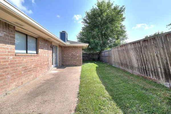 a backyard of a house with plants and wooden fence