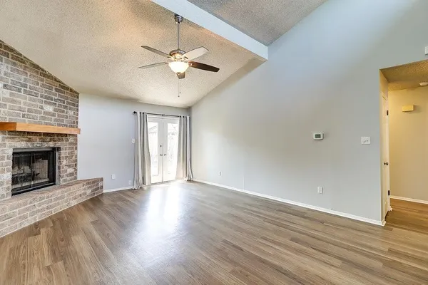 a view of an empty room with wooden floor and a fireplace