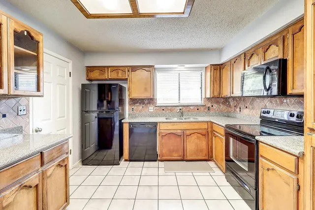 a kitchen with stainless steel appliances granite countertop a stove a sink and a microwave
