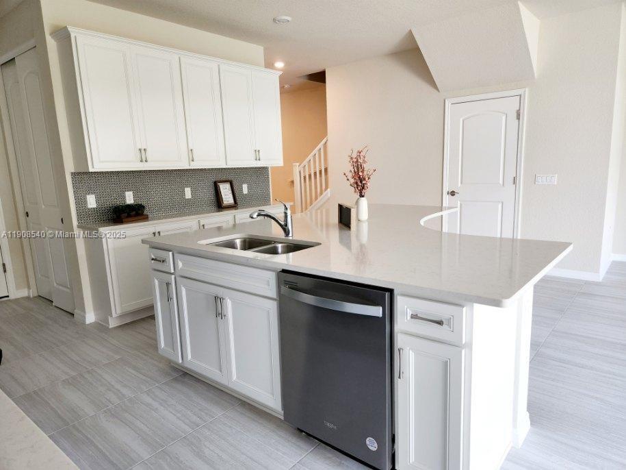 a kitchen with stainless steel appliances granite countertop a sink a stove and white cabinets with wooden floor