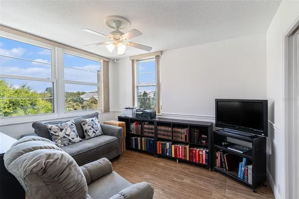 a living room with a bed furniture flat screen tv and a large window