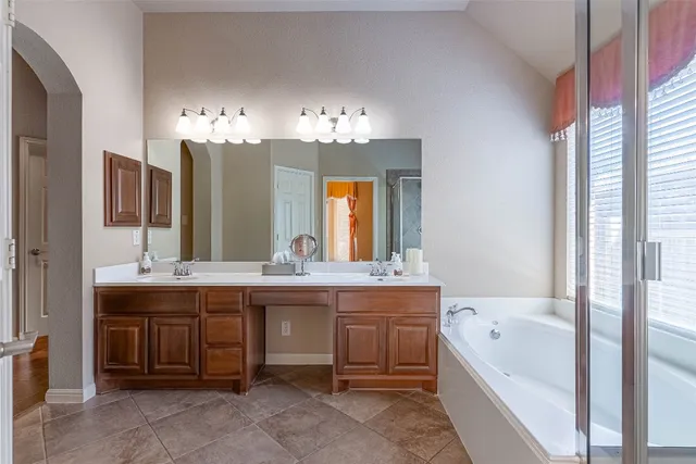a bathroom with a tub a sink and a large mirror