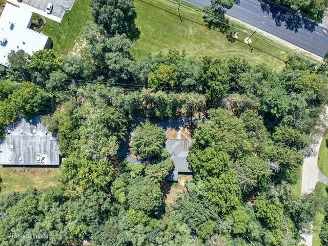 an aerial view of residential house with outdoor space and trees all around