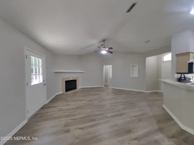 a view of an empty room with a window and fireplace