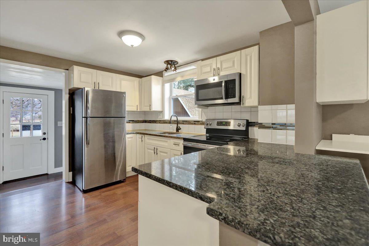 5145 Spruce Road Emmaus, PA 18049 - Photo 7 of 26 a kitchen with granite countertop a refrigerator a stove a microwave a sink and dishwasher with wooden floor