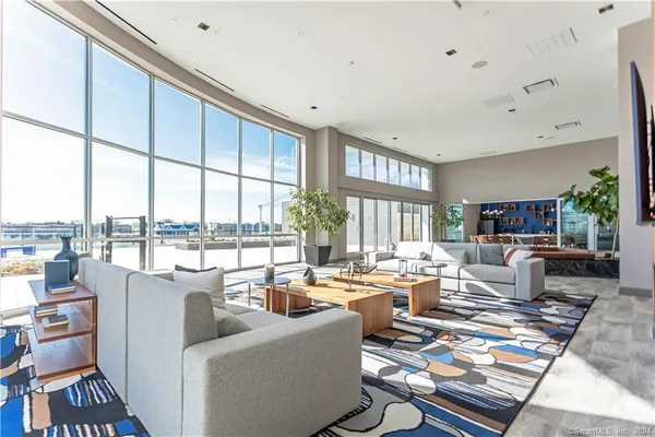 a living room with furniture large windows and wooden floor