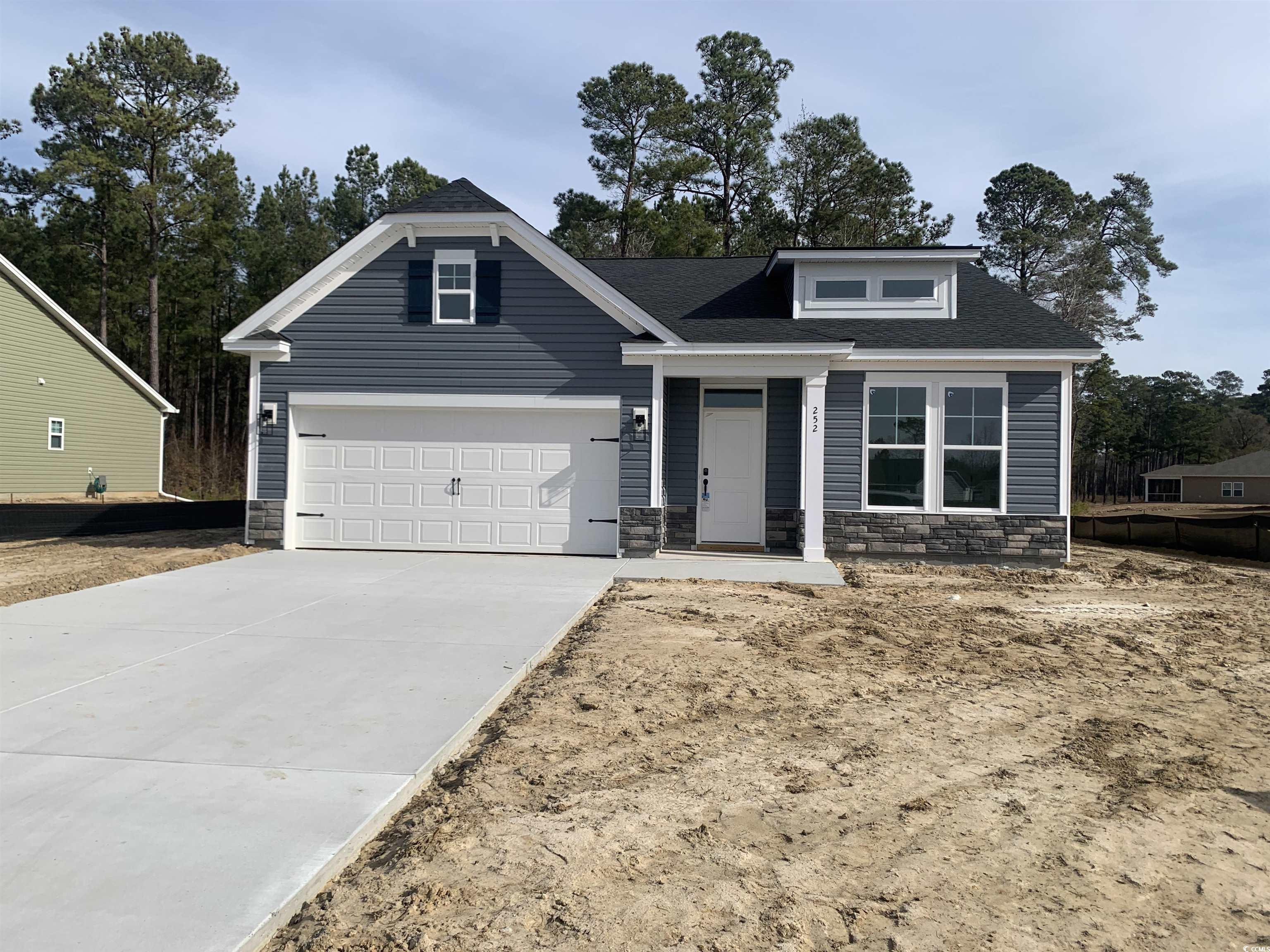 View of front of home featuring stone siding, driveway, a shingled roof, and covered porch
