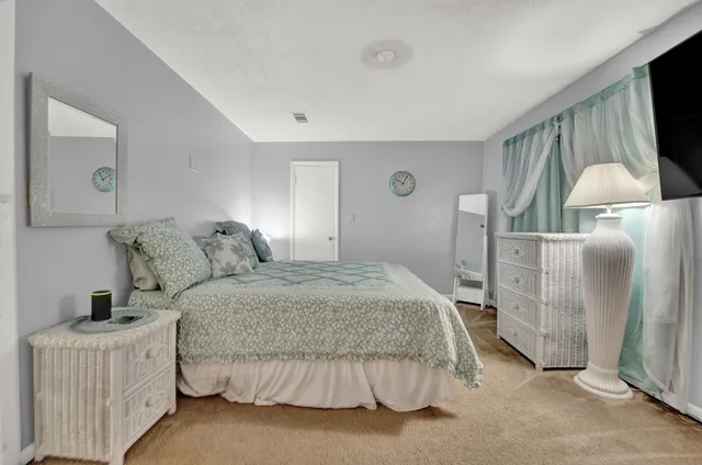 a bedroom with a bed and a flat tv screen on dresser
