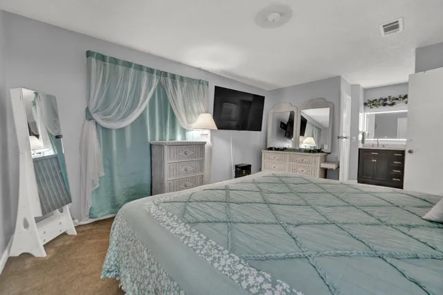 a bedroom with a large bed a flat tv screen and a dresser
