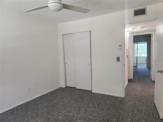 an empty room with closet and a chandelier fan