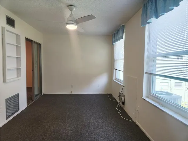 an empty room with windows and fan