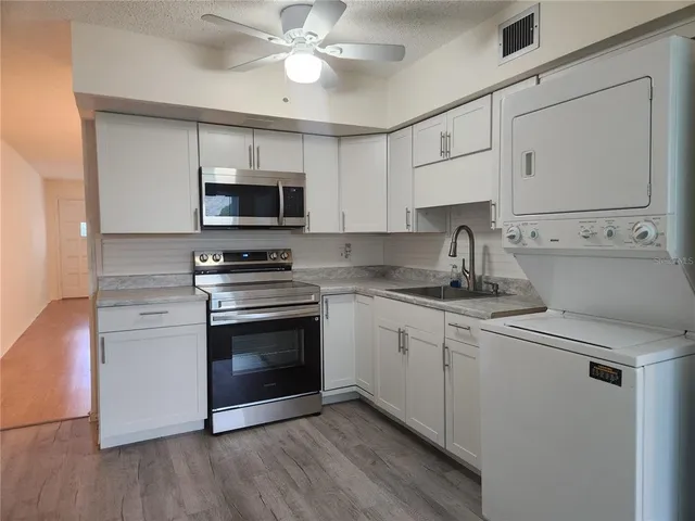 a kitchen with stainless steel appliances a sink cabinets and a wooden floor