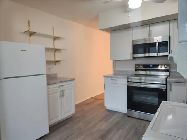 a kitchen with cabinets stainless steel appliances and wooden floor