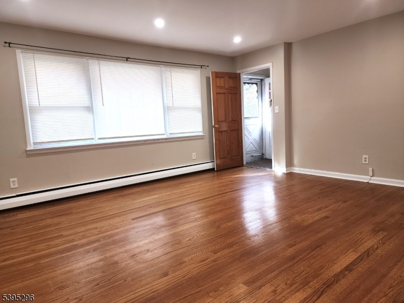 84 Reservoir Avenue Butler, NJ 07405 - Photo 5 of 20 an empty room with wooden floor and windows with curtains view