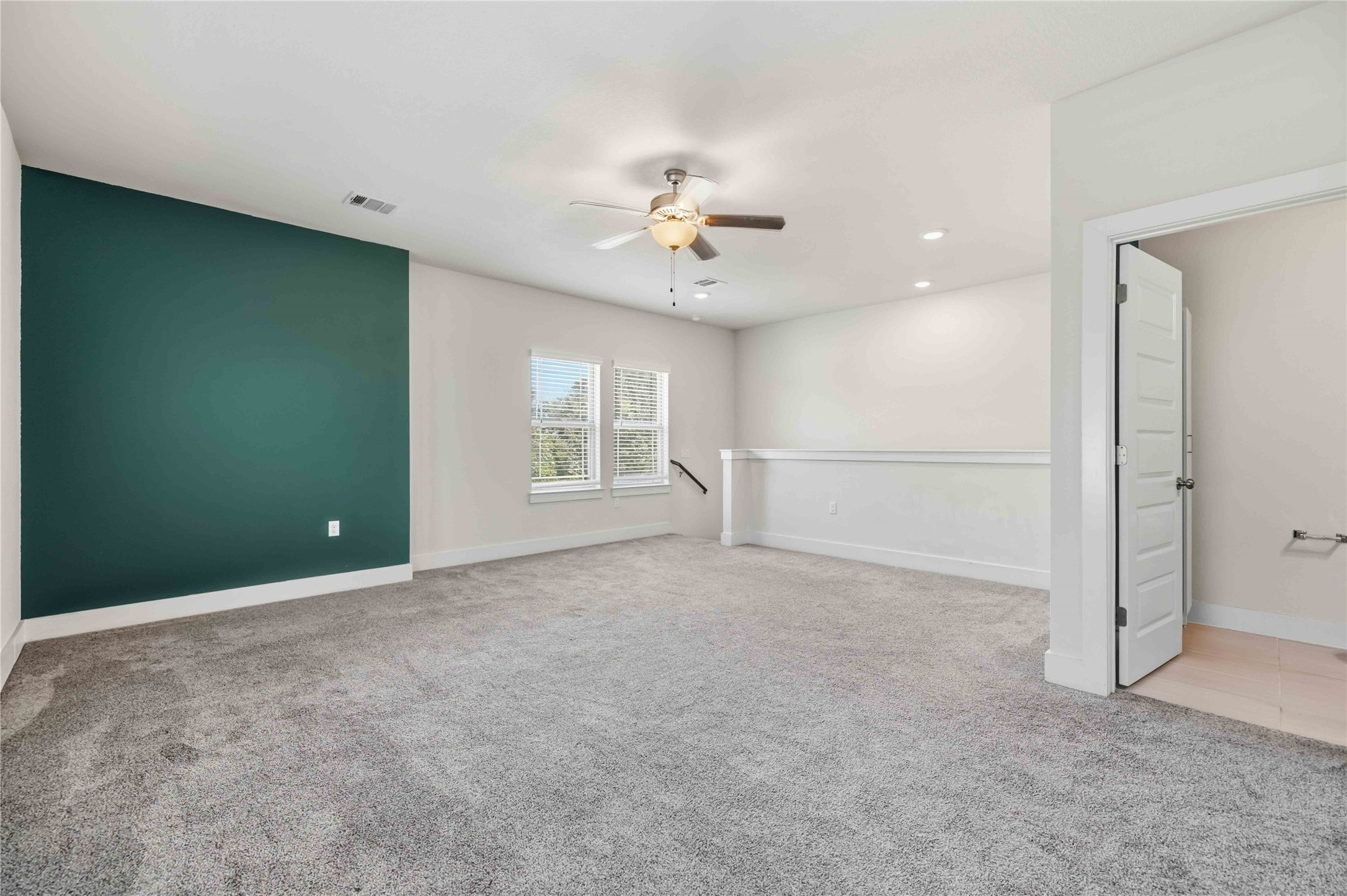 1722 Rowdy Loop, Unit 7 Leander, TX 78641 - Photo 21 of 37 Spacious upstairs loft featuring plush carpeting, a ceiling fan, and a striking accent wall, perfect for a cozy retreat or entertainment area.