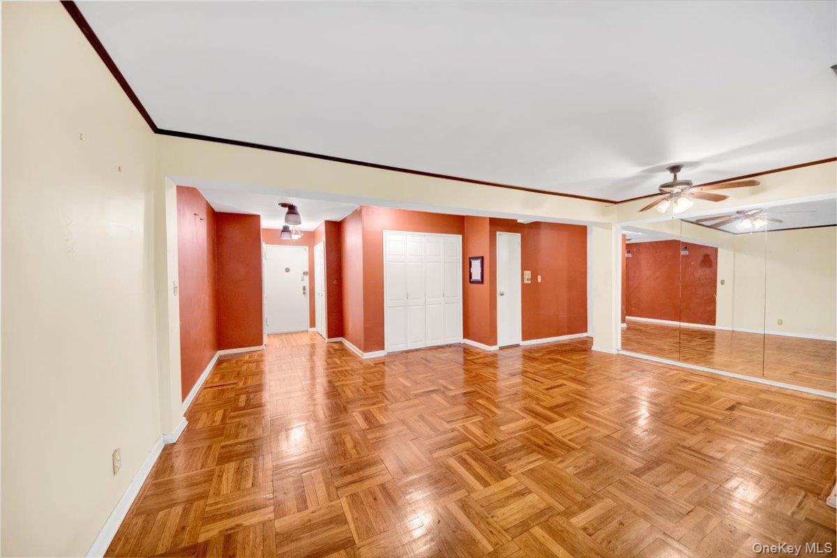 a view of empty room with wooden floor and fan