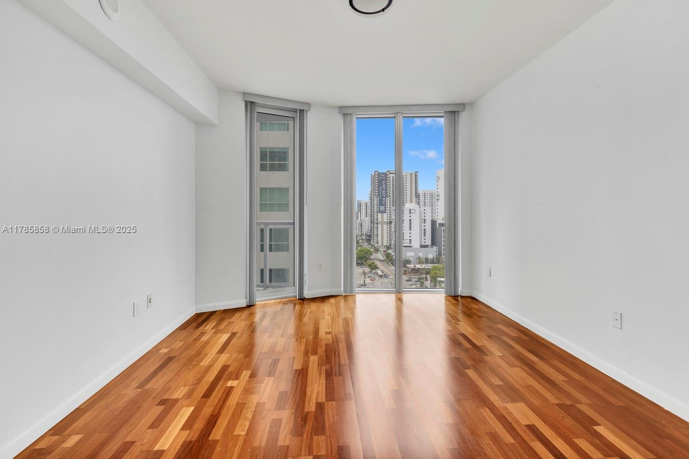 185 Southwest 7th Street, Unit 1508 Miami, FL 33130 - Photo 10 of 30 a view of an empty room with wooden floor and a window