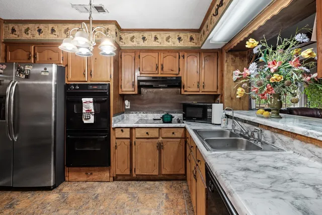a kitchen with granite countertop a sink stainless steel appliances a counter top space and cabinets