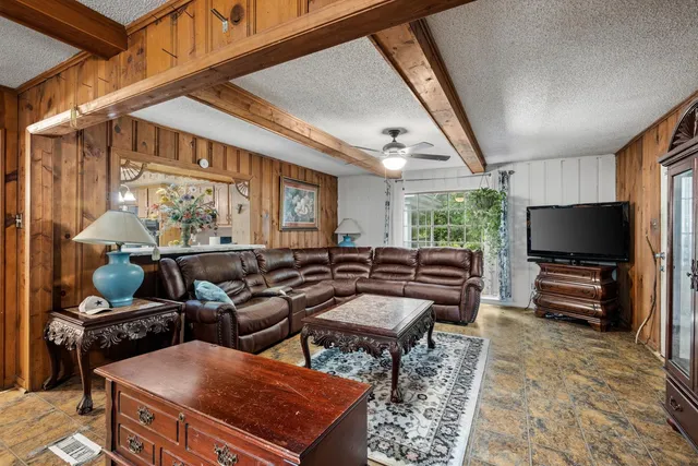 a living room with furniture a flat screen tv and floor to ceiling window
