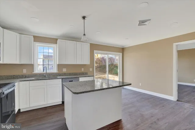 a kitchen with stainless steel appliances granite countertop a sink a stove a refrigerator and island with wooden floor