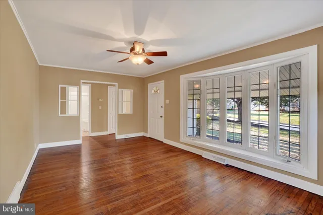 a view of an empty room with a window and wooden floor