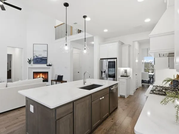 a kitchen with a stove a sink dishwasher a kitchen island with wooden cabinets and floor