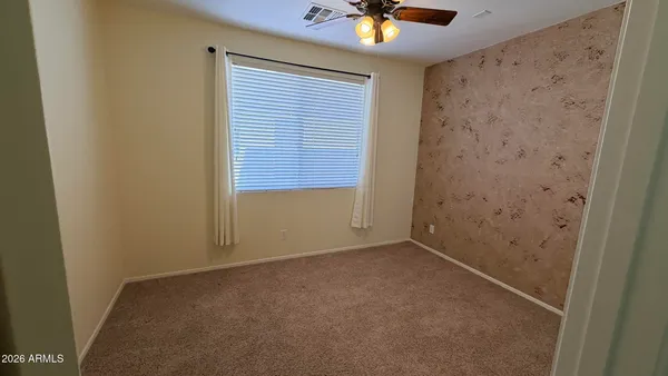 an empty room with a chandelier fan and a window