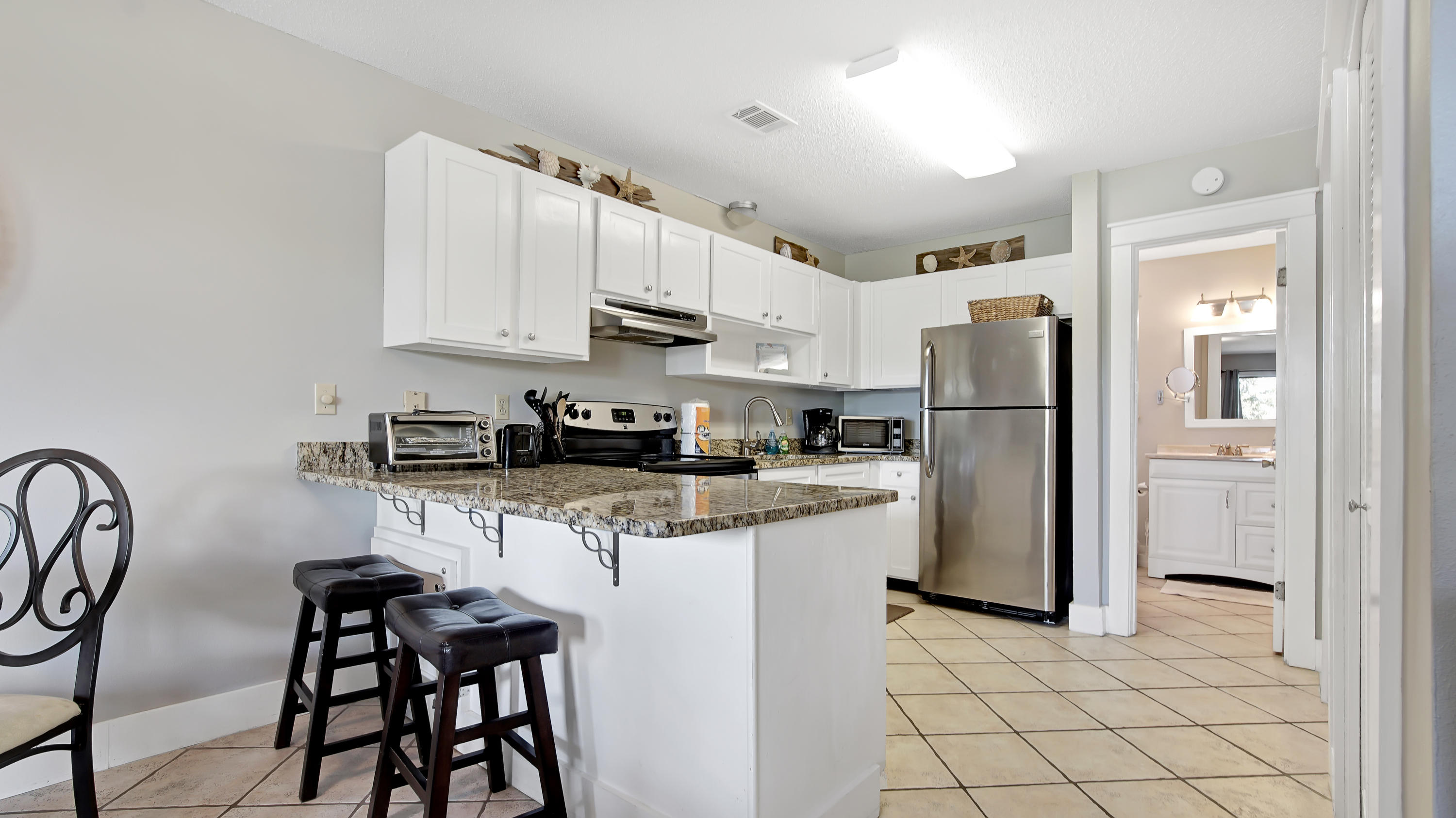 3799 East County Highway 30A, Unit F2 Santa Rosa Beach, FL 32459 - Photo 14 of 25 a kitchen with stainless steel appliances a refrigerator a stove a sink dishwasher and white cabinets with wooden floor