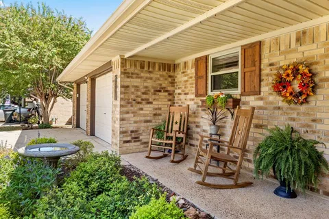 a view of a patio with table and chairs potted plants and a large tree