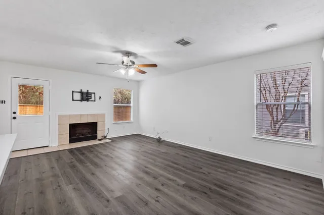 an empty room with windows fireplace and wooden floor